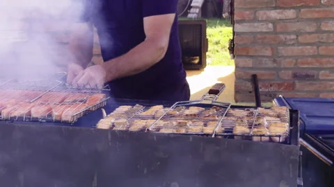Chef flips the skewer of red salmon fish to the other side for baking. Picnic Stock Footage 279450498