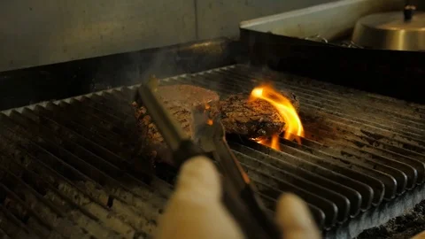 Chef flips steak and hamburger meat on pro flame grill Stock-Footage 94246415