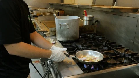 Chef flips vegetables in pan on stove in professional kitchen Stock Footage 94253334