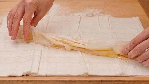 Chef folding buttered layers of phyllo dough into rolls Stock Photos