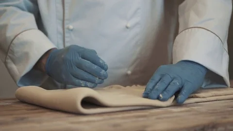 Chef folding raw dough for baking croissants on a wood cutting board Stock Footage 78031660