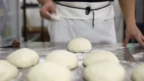 Chef forming the dough on a floured surface and kneading it with his hands. Stock Footage 117780007