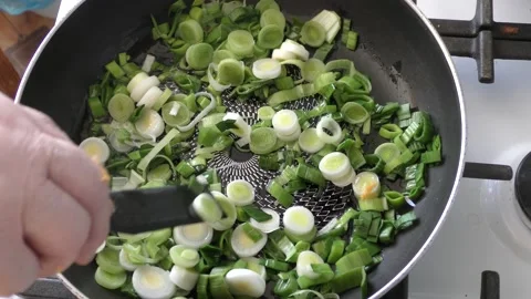 The chef fries leeks in a pan Stock Footage 164857898