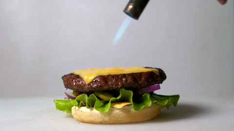 Chef fries slice of cheese on beef cutlet using gas burner Stock Footage 152649626