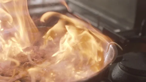 Chef Frying beef on fire throwing them in a frying pan. Slow motion video Stock Footage 114977596