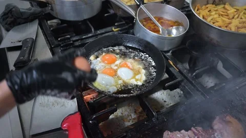 Chef frying eggs and grilling meat in a busy restaurant kitchen Stock-Footage 323792512