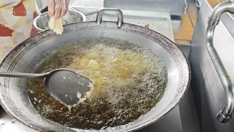 Chef frying flour-coated fish fillets in a large wok. Video stock 342687015
