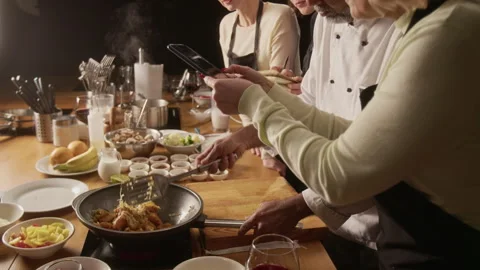 Chef Frying Meat in Pan While Woman Filming It During Cooking Master class Stock Footage 332575643