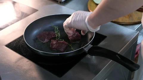Chef is frying pieces of beef meat with rosemary in the boiling oil Stock Footage 130920575