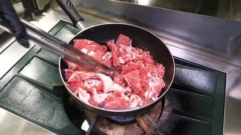 Chef frying thinly sliced beef in a pan over high flame in professional kitchen Stock Footage 324713464