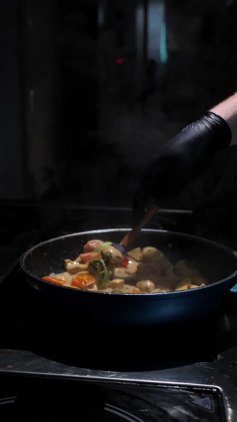 Chef frying vegetables with meat mixing in a frying pan. Chef cooking Stock Footage 309463499