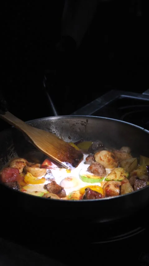 Chef frying vegetables with meat, stirring them with cream in a frying pan. Stock Footage 309463356