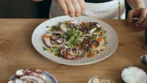 Chef garnishing delicious looking octopus carpaccio dish on a cutting board. Clo Stock Footage 199458967