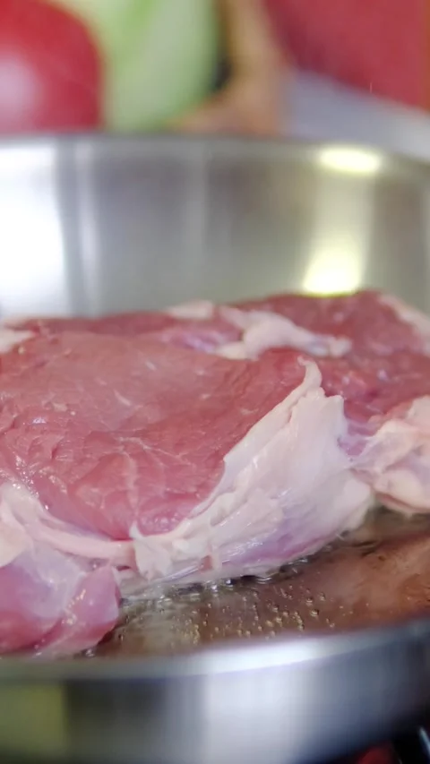 Chef gently presses raw beef steak by hand as it begins searing in hot Stock Footage 346182100
