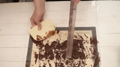 Chef getting rid of the odd chocolate on the forms for candiies closeup Stock Footage 74589330