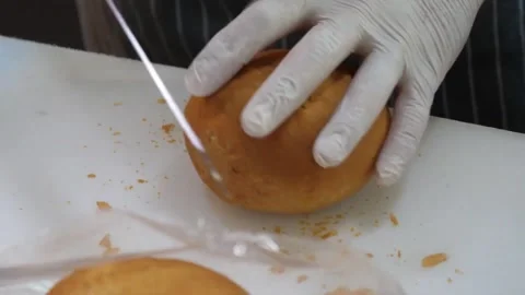 Chef in Gloved Hands Slicing Fresh Bun on Cutting Board Vídeo Stock 343587354