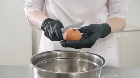 Chef in gloves breaks chicken egg with knife over bowl Stock Footage 137932050