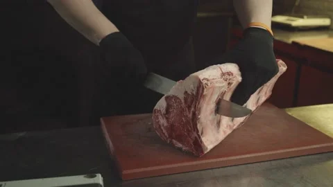 A chef with gloves cuts a large piece of beef in the kitchen. Close-up Stock Footage 157810874