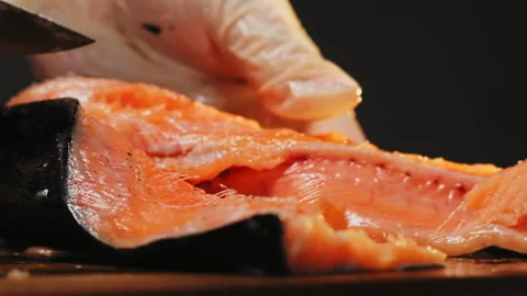 Chef in gloves cuts red fish into pieces with sharp knife 库存影片 149811749