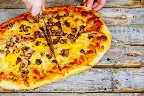 Chef in gloves cutting hot ready pizza by rolling pizza cutter, closeup Stock Photos