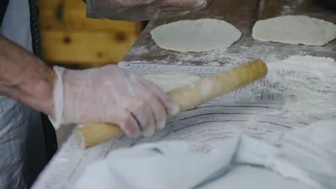 A chef in gloves makes tortillas from dough for cooking them in a frying pan Stock Footage 252195061