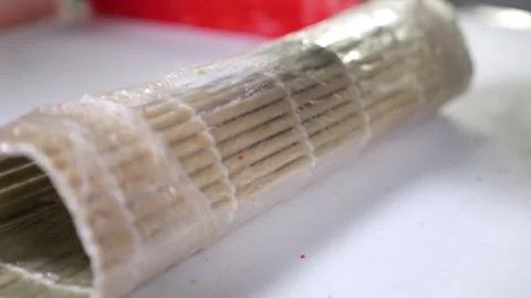 A chef in gloves prepares sushi, he slices sushi with salmon with a large knife. Stock Footage 346442252
