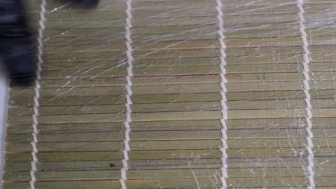 A chef in gloves prepares sushi rolls on a bamboo mat in a professional kitchen. Stock Footage 323911684
