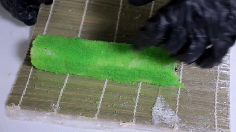 A chef in gloves prepares sushi rolls on a bamboo mat in a professional kitchen. Stock Footage 327644031