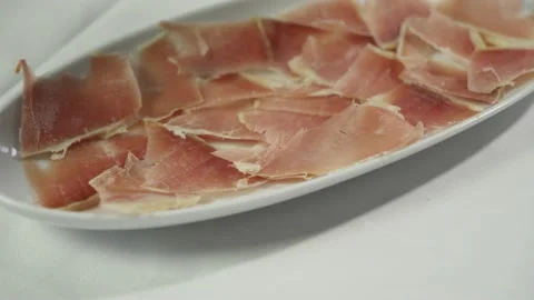 A chef in gloves puts sliced ham on a white plate. Close-up Stock Footage 157810869