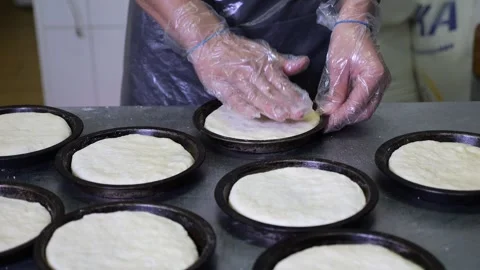 A chef in gloves putting dough into small baking pans in the restaurant kitchen Stock Footage 319004651