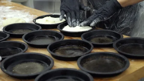 A chef in gloves putting dough into small baking pans in the restaurant kitchen Stock Footage 341550934