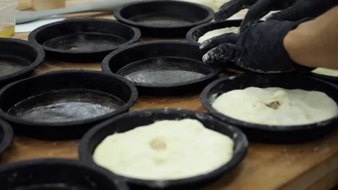 A chef in gloves putting dough into small baking pans in the restaurant kitchen Stock Footage 341868063