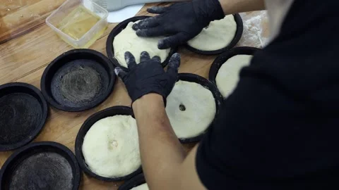 A chef in gloves putting dough into small baking pans in the restaurant kitchen Stock Footage 341868134