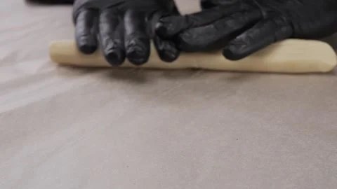A chef with gloves rolls out the dough on the table. Stock Footage 308521076