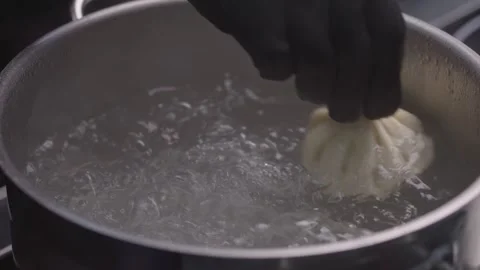 Chef in gloves throws khinkali into saucepan of boiling water. Stock Footage 313981712