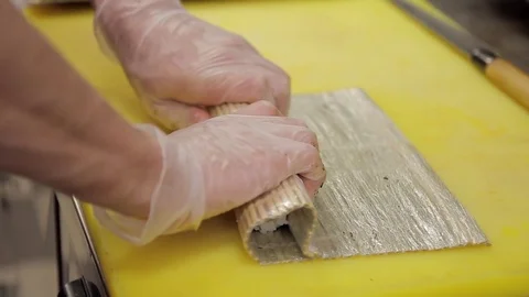 A chef with gloves on a yellow table forms rolls with a mat Stock Footage 76028143