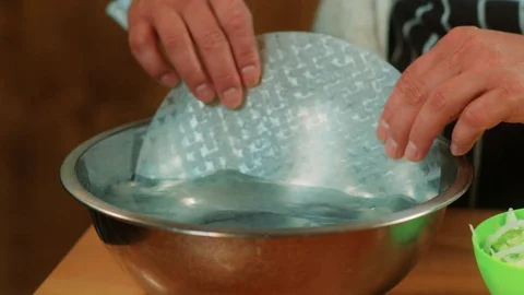 Chef grabbing and dunking Vietnamese rice spring rolls wrapper in water Stock Footage 83321302