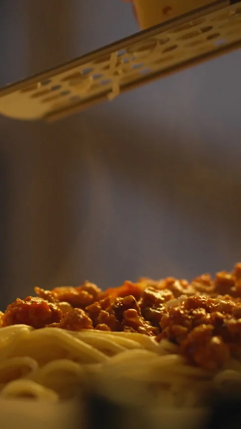 A chef grates cheese over a plate of spaghetti bolognese using a grater prep Stock Footage 341285059