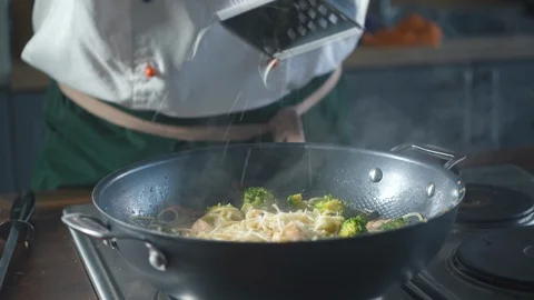 Chef grating cheese parmesan in a pan with italian pasta in a restaurant kitchen Stock-Footage 124710596