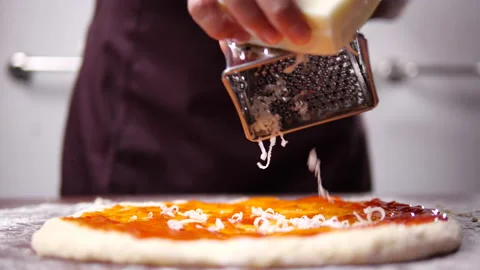 Chef grating cheese into pizza dough in slow motion Stock Footage 136075854