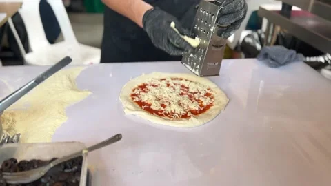 Chef grating cheese on pizza preparing for baking. Stock Footage 232927759