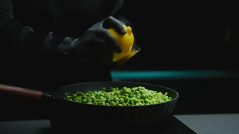 Chef grating fresh lemon zest over cooking peas Stock Footage 319745541