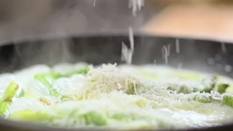 Chef grating parmesan cheese on asparagus in a creamy sauce in a frying pan. Stock Footage 151196121