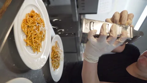 Chef grating parmesan cheese over trofie pasta dishes with tomato sauce in Stock Footage 236593594