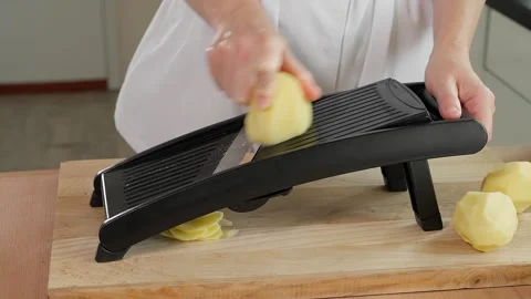 Chef grating potatoes into slices on a mandolin grater, preparing healthy food Stock Footage 270151014