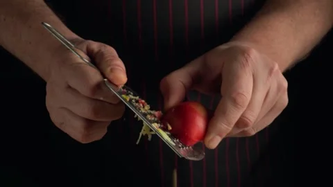 Chef grating a red apple with a stainless steel grater, showcasing the peeling Stock Footage 337098592