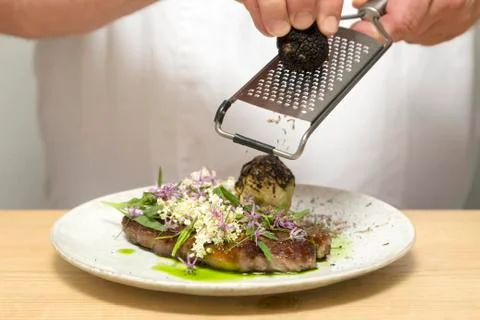 Chef grating truffle on meat Stock Photos