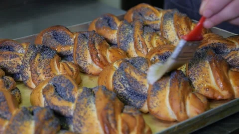 A chef greasing poppy seed buns with butter with a brush in a restaurant kitchen Stock Footage 318138624