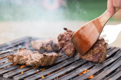 Chef grilling beef steaks on open flame BBQ. Stock Photos
