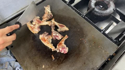 Chef grilling delicious lamb chops on a griddle in a restaurant kitchen Stock Footage 344100280